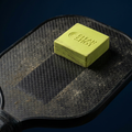 Pickleball paddle eraser cleaning a carbon fiber paddle face